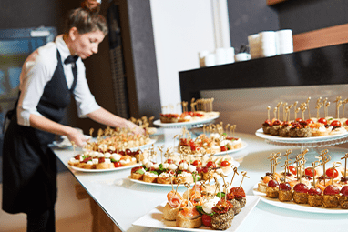 Restaurant waitress serving table with food.
