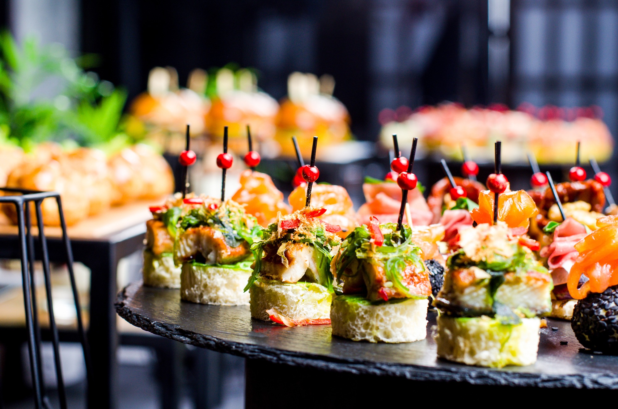 Set of beautiful canapes on black stone plates. Buffet table. Catering.